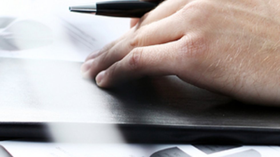 ręka z długopisem opiera się na stole